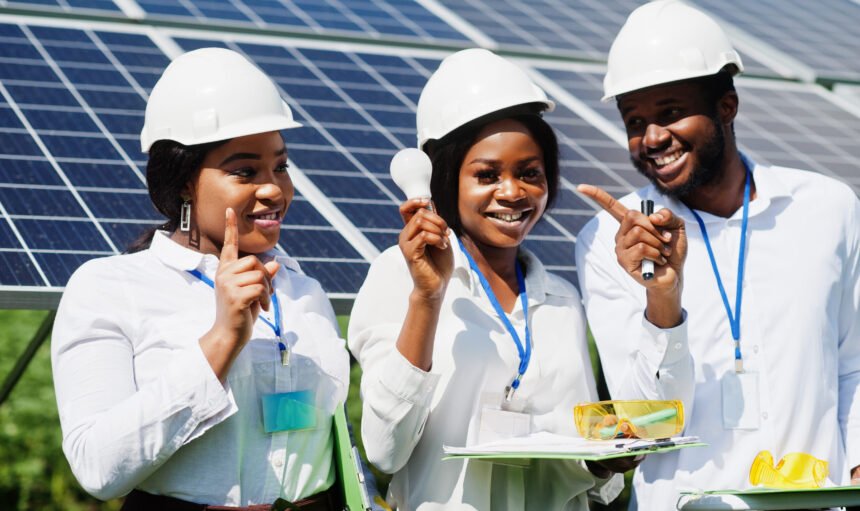 African american technician checks the maintenance of the solar panels. Group of three black engineers meeting at solar station. Hold led bulb.