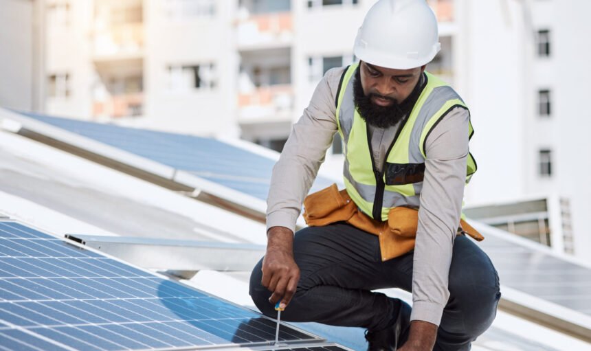 African engineer man, screwdriver and solar panel on roof for maintenance, industry or thinking in city. Technician, builder and tools for photovoltaic tech, helmet and sustainable renewable energy.
